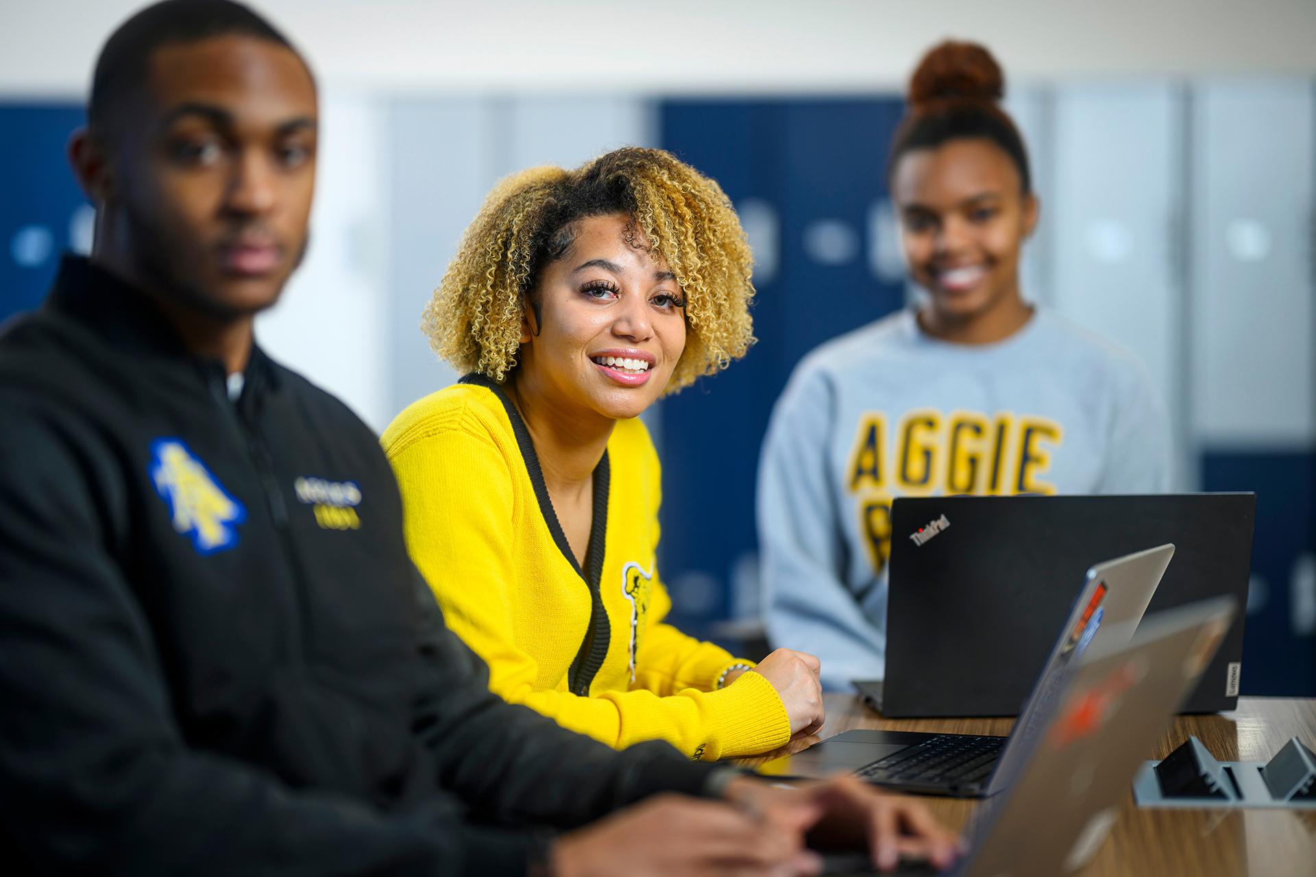 three students wearing A&T gear with laptops