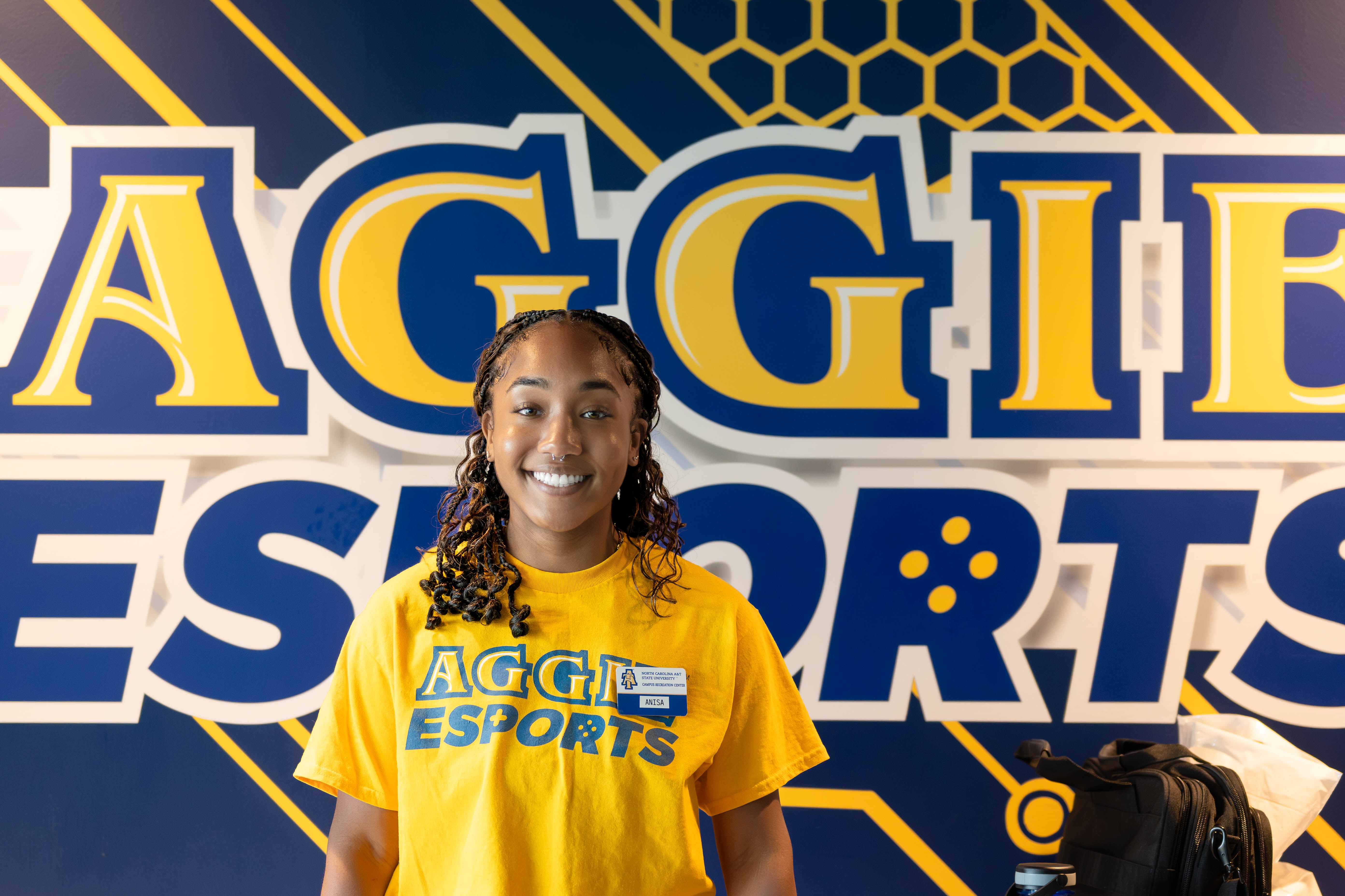 Aggie Esports employee in front of Aggie Esports sign