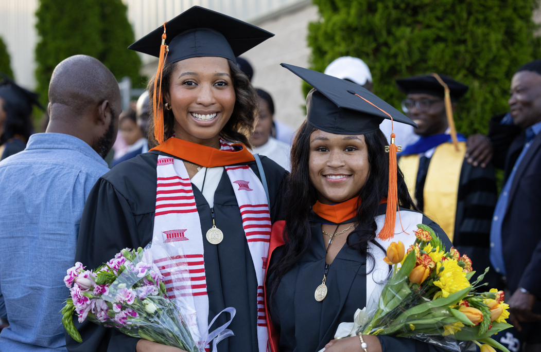 Two graduate students at the 2025 Spring Graduate Commencement ceremony.